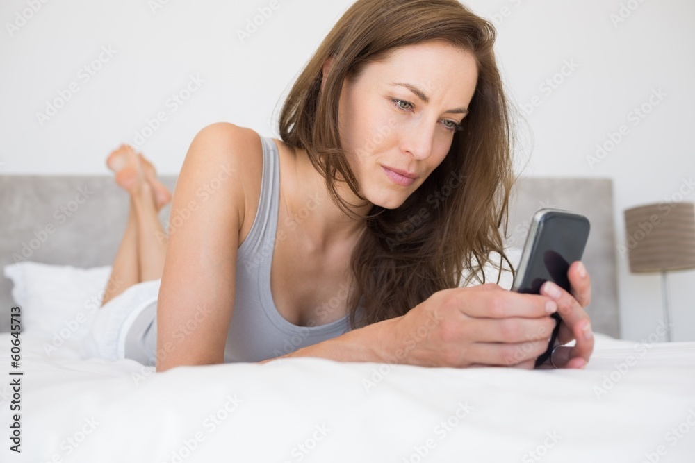 Relaxed young woman text messaging in bed Relaxed young woman text messaging in bed