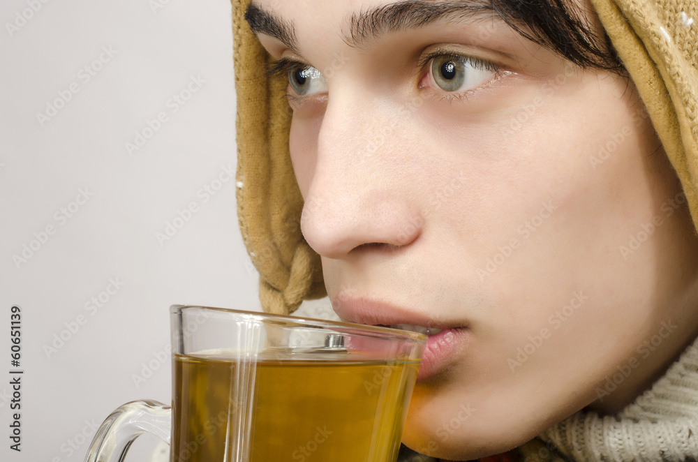 Man wearing sweater, gloves, scarf, hat, drinking cup of tea Man wearing sweater, gloves, scarf, hat, drinking cup of tea