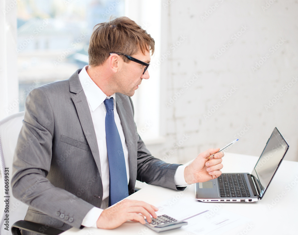 businessman with computer, papers and calculator