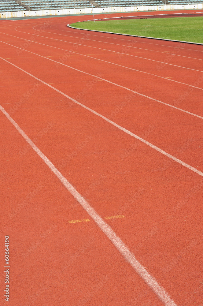 Orange racecourse with white line and green yard.