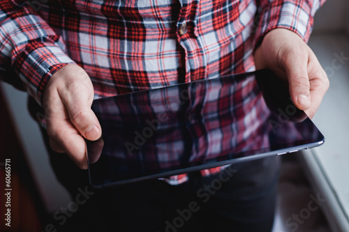 The man uses a tablet PC. Modern gadget in hand.