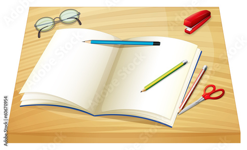 A table with an empty notebook, pencils, stapler and a scissor