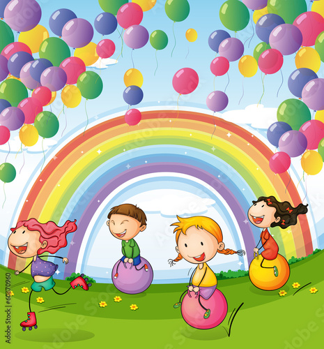 Kids playing with floating balloons and rainbow in the sky