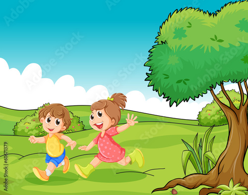 Two adorable little kids playing at the hilltop near the tree