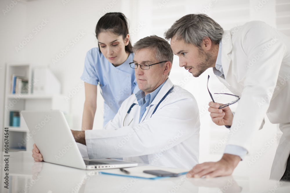 medical team discussing around a computer medical team discussing around a computer