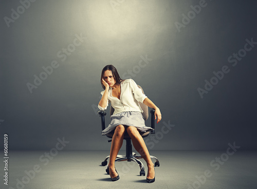 Fotografi woman sitting on the chair in empty dark room