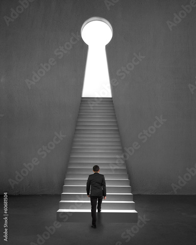 Businessman climbing on stair to key shape door concrete backgro