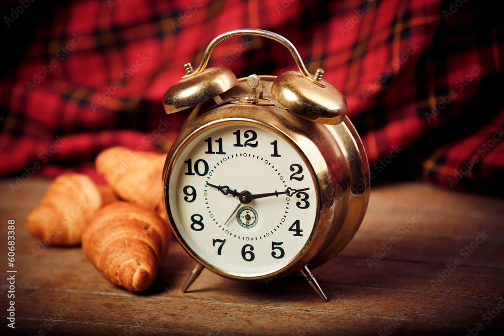 Three croissants at table and alarm clock Three croissants at table and alarm clock