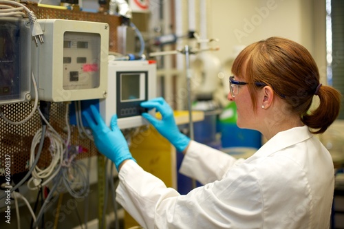 Woman adjusting Machine in Laboratory