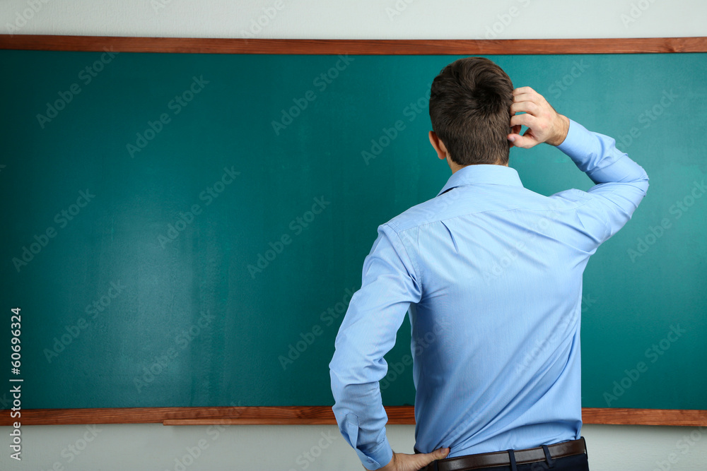 Young teacher near chalkboard in school classroom Young teacher near chalkboard in school classroom