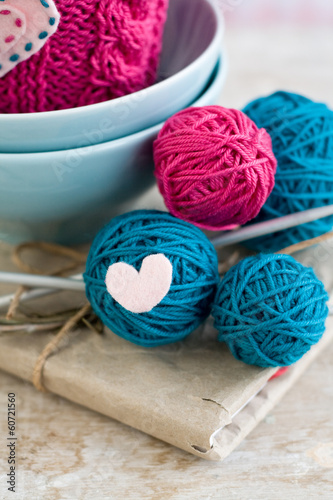 Bright balls of yarn in blue plates and heart made ​​of felt