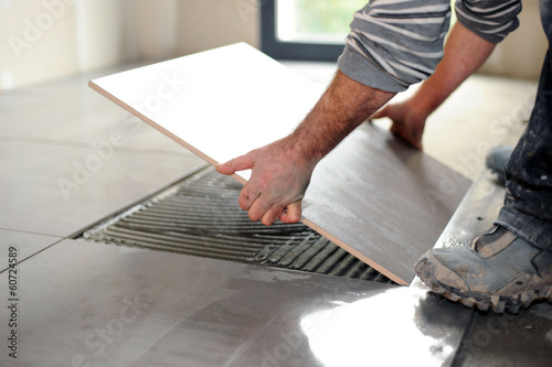 Fotografie Man laying floor tiles