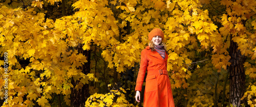 The girl in an orange coat of yellow maple leaves.