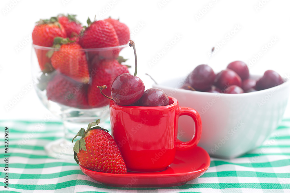 Cherries and strawberry in a ceramic and glass bowl on checkered Cherries and strawberry in a ceramic and glass bowl on checkered