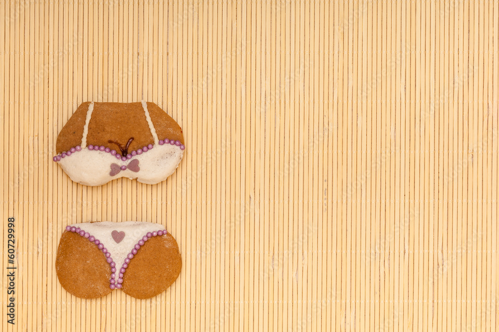 White violet bikini shape gingerbread cake cookie on bamboo mat White violet bikini shape gingerbread cake cookie on bamboo mat
