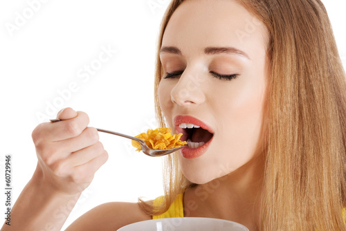Beautiful caucasian slim woman eating corn flakes.