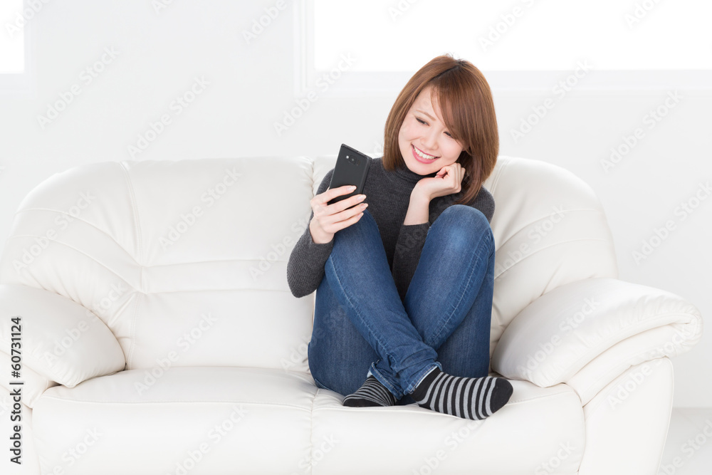 ソファでスマートフォンを見る女性 ソファでスマートフォンを見る女性