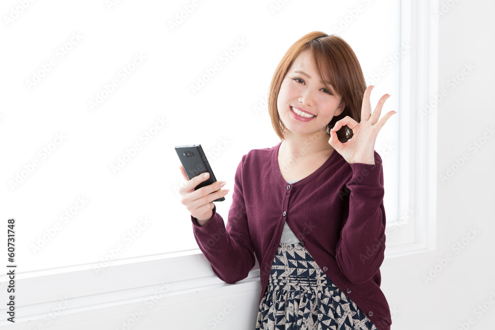 窓辺でスマートフォンを見る女性 窓辺でスマートフォンを見る女性