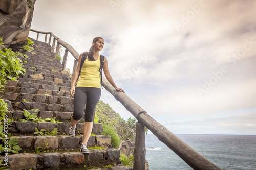 young woman hiking happy on stairway on the ocean