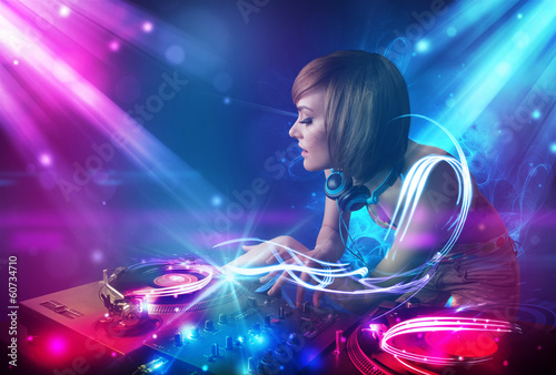 Energetic Dj girl mixing music with powerful light effects © ra2 studio