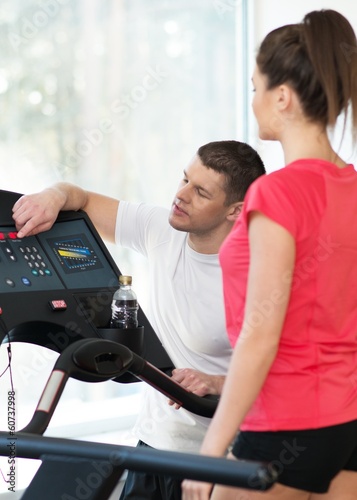 Trainer explains to a young woman how to use treadmill 