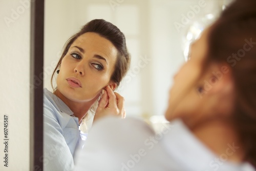 Attractive woman putting on her earrings