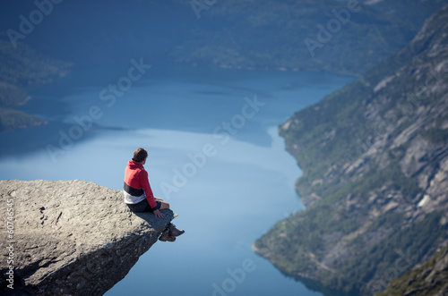 man sitting on trolltunga rock in norway