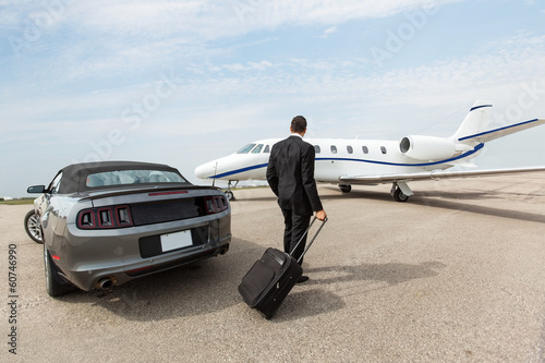 Картината върху платно Businessman Standing By Car And Private Jet At Terminal