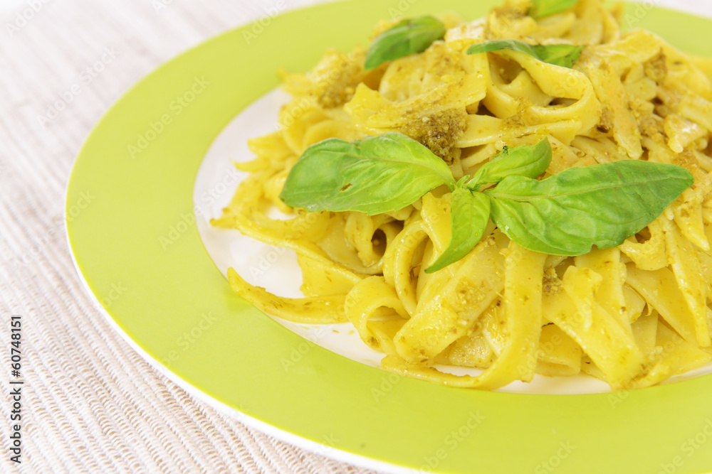 Delicious pasta with pesto on plate on table close-up