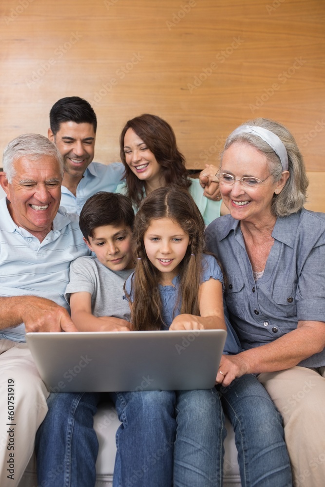 Extended family using laptop on sofa in living room Extended family using laptop on sofa in living room