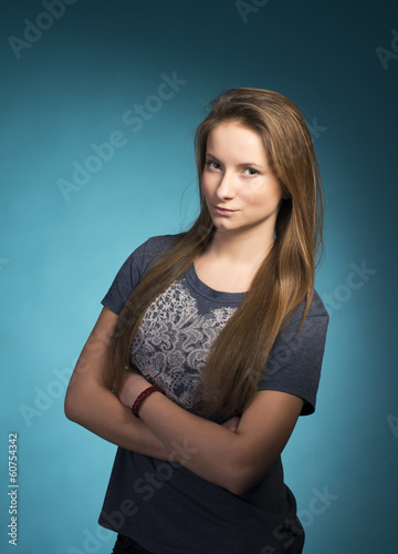 Half-length portrait of pensive young girl on blue background.