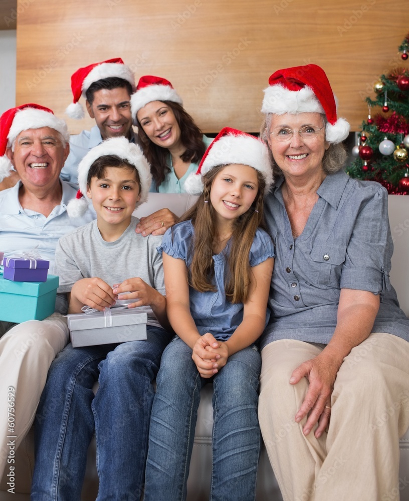 Extended family in Christmas hats with gift boxes in living room Extended family in Christmas hats with gift boxes in living room