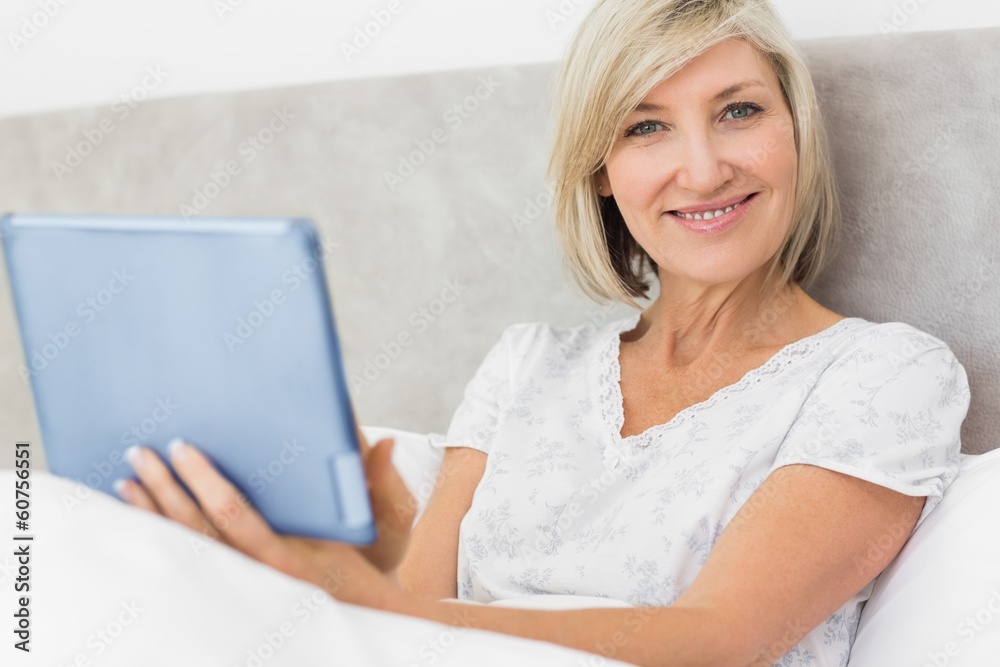 Smiling mature woman using digital tablet in bed Smiling mature woman using digital tablet in bed