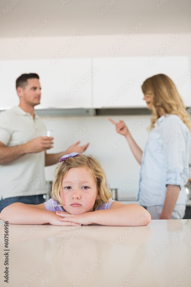 Sad girl leaning on table while parents conflicting Sad girl leaning on table while parents conflicting