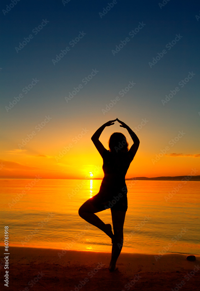 Silhouette of the girl on a sunset on the ocean coast