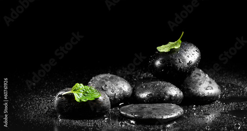 Photography Zen stones with mint leaves on a black background