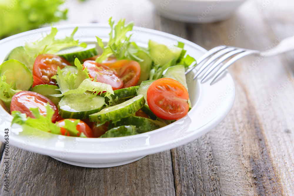 Fresh salad from cucumbers and tomatoes on white plate Fresh salad from cucumbers and tomatoes on white plate
