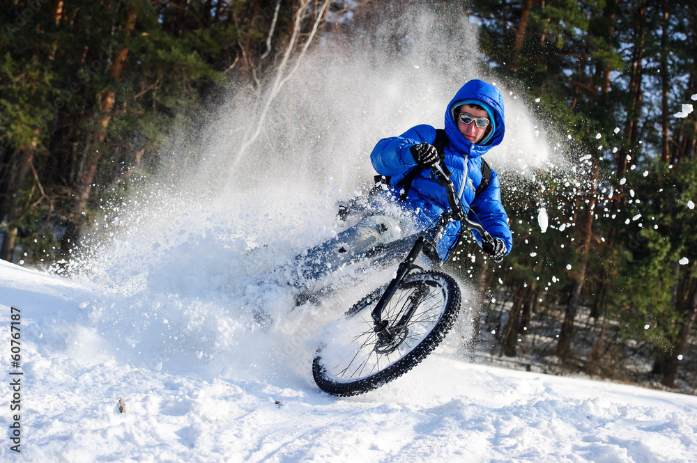 Fototapeta premium Cyclist riding on a mountain bike in the snow winter forest