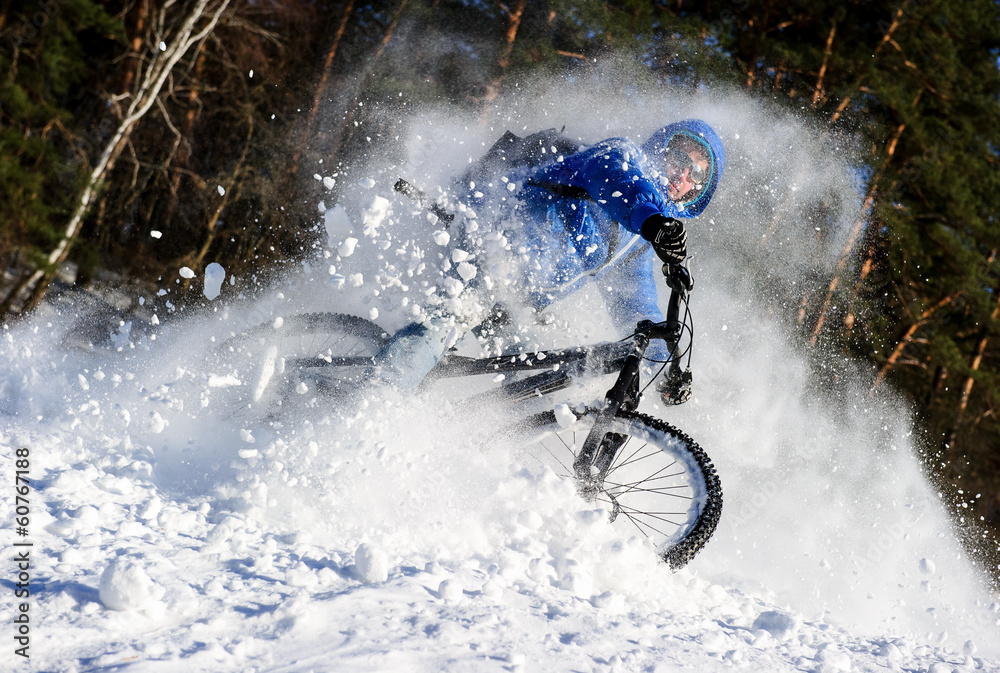 Naklejka premium Cyclist riding on a mountain bike in the snow winter forest