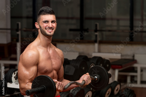 Men In The Gym Performing Biceps Curls With A Barbell