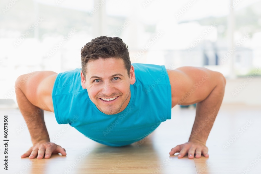 Portrait of a smiling young man doing push ups Portrait of a smiling young man doing push ups