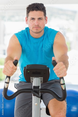 Serious young man working out at spinning class