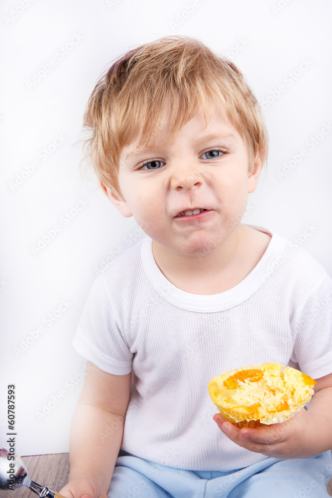 Little boy with eating cheesecake muffin.