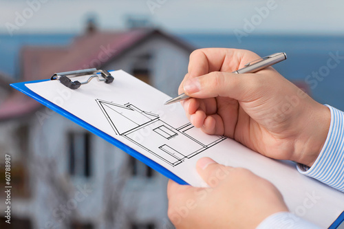 businessman  draws a drawing of a house on the background of an