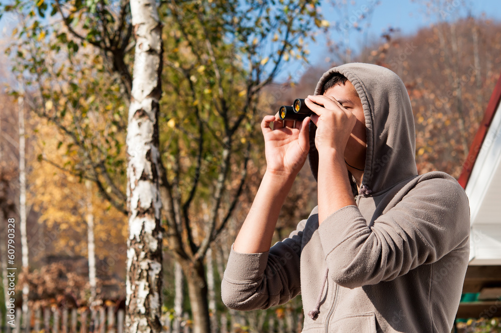 Young man with binoculars watching the nature, Man with binocula Young man with binoculars watching the nature, Man with binocula