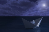 Paper boat floating in the sea at night
