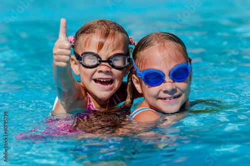 two happy little girls playing in the swimming pool