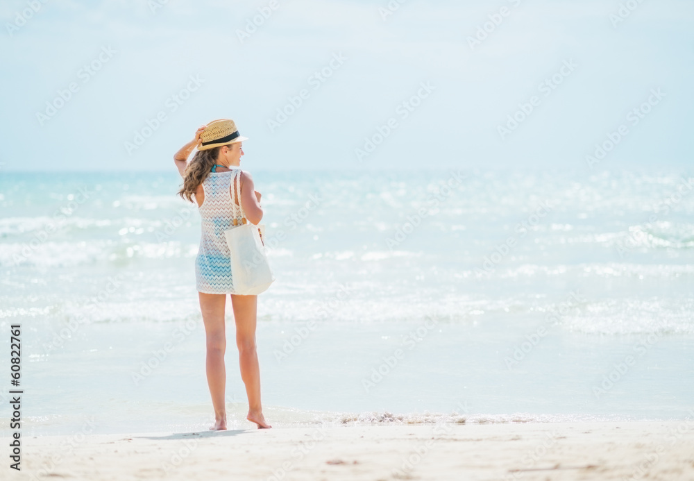 Young woman standing on beach. rear view