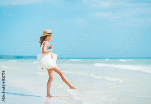 Young woman with hat and bag having fun time on sea coast