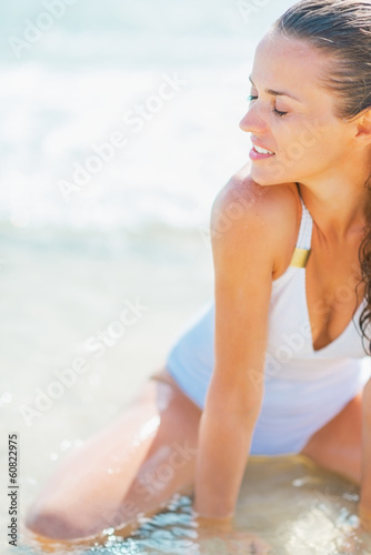 Young woman in swimsuit enjoying sitting on sea shore